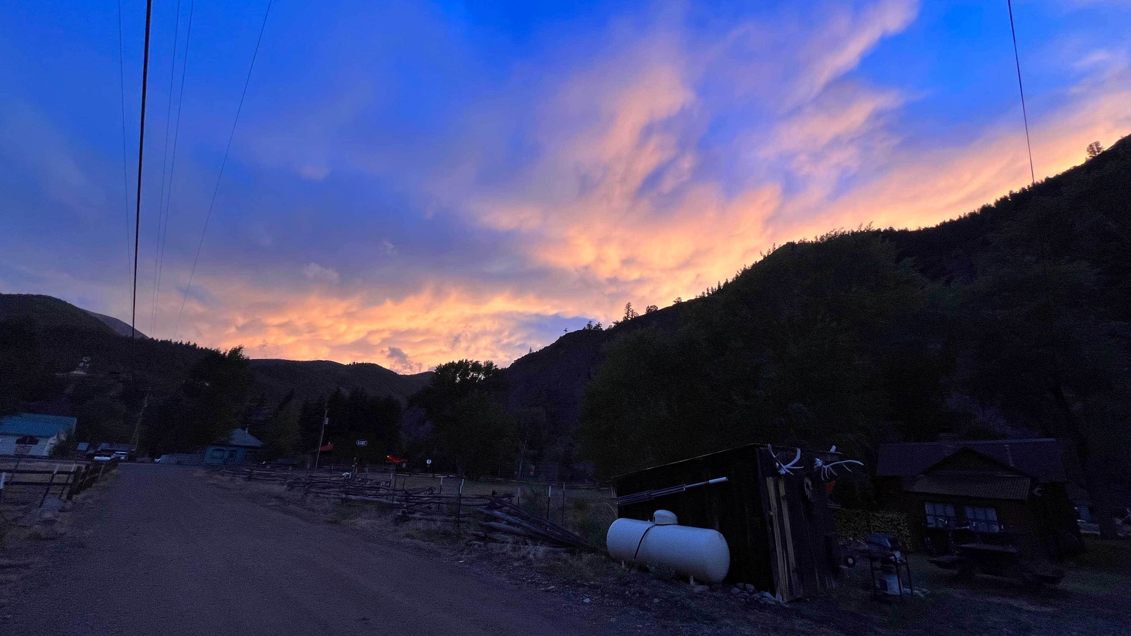 Fiery sunset with orange and pink clouds over a silhouetted mountain town