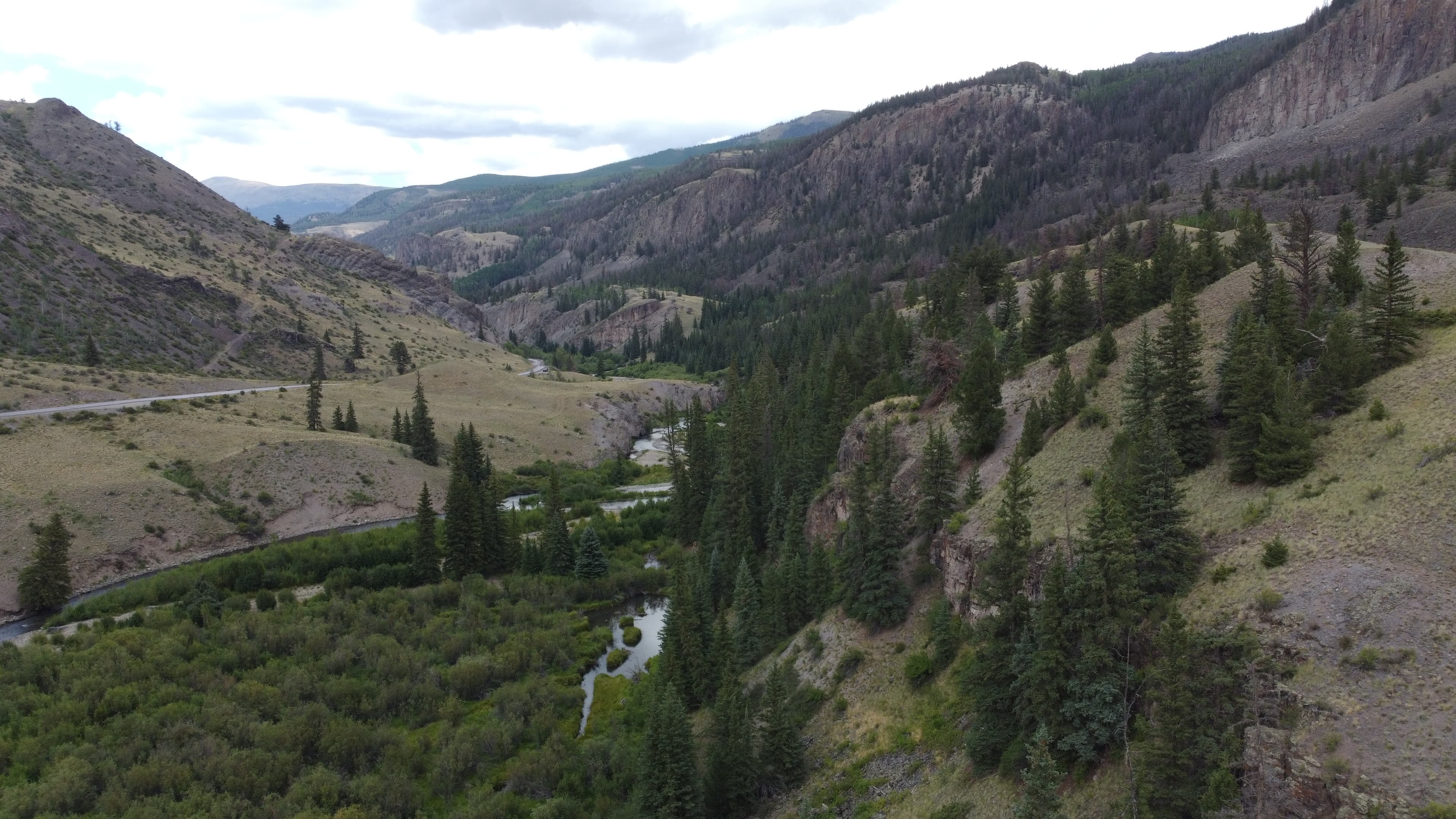 Drone shot of mountain valley with winding river and road